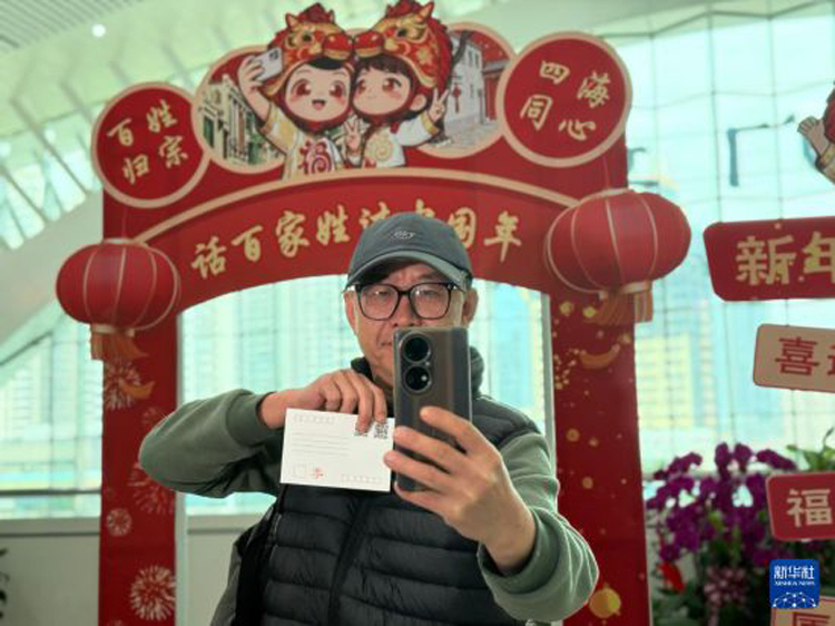 小小電商年貨火熱是兩岸經貿合作共贏的縮影_fororder_2月10日，在廈門站“話百家姓 過中國年”主題文化活動現場，臺胞李高雄拿著專屬姓氏明信片自拍留念。新華社記者 付敏 攝