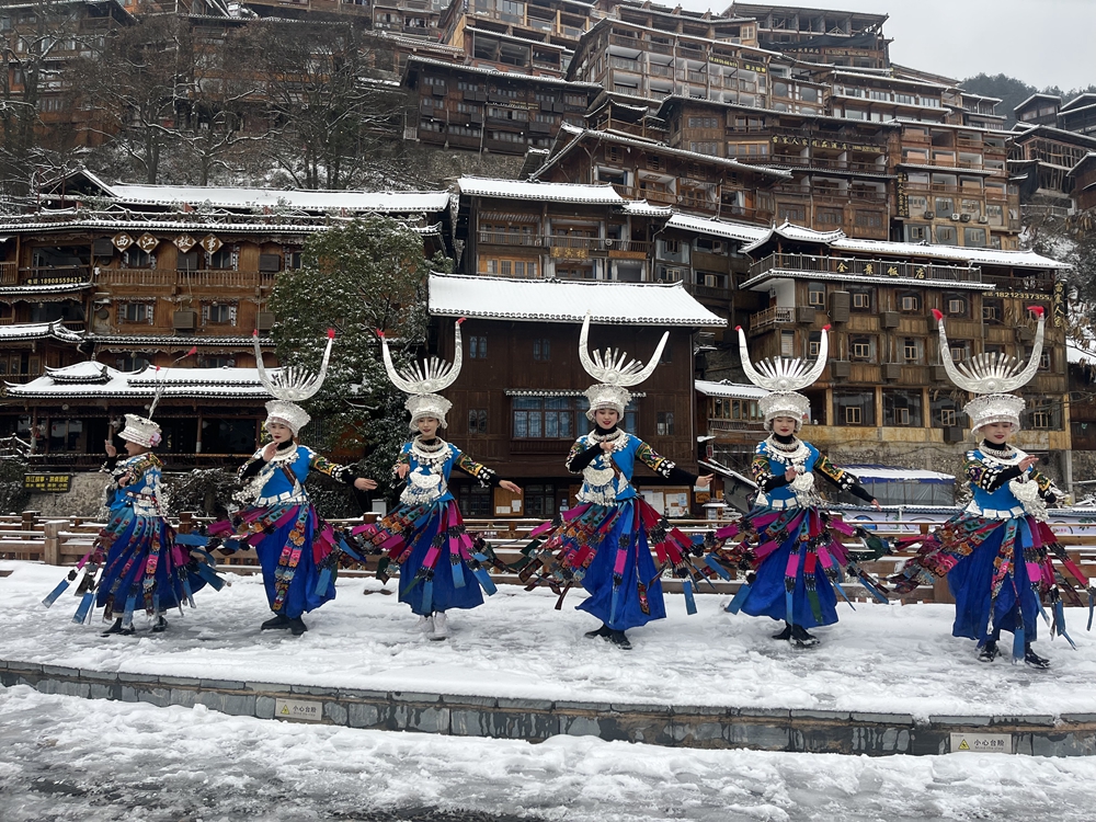 貴州雷山西江千戶苗寨迎來降雪  冬日雪景如畫_fororder_1月22日，貴州省雷山縣西江千戶苗寨迎來2024年第一場降雪。圖為苗寨女孩在雪中翩翩起舞。