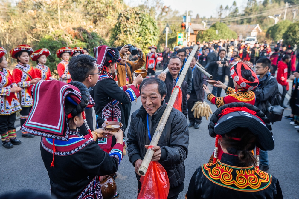 貴州畢節：鄉鄰一家親 共慶彝族年_fororder_2023年11月19日，村民在貴州省畢節市百里杜鵑管理區普底鄉迎豐村為前來參加彝族年的嘉賓送上攔門酒。 (4)