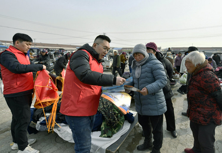 河北遷安：氣象防災減災知識“趕大集”_fororder_志願者向攤主發放宣傳手冊，講解氣象科普知識。梁玉水攝