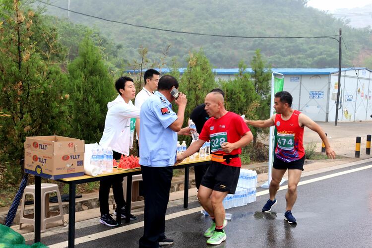 （原創）河北唐縣：十公里健康跑比賽鳴槍開跑_fororder_補給點志願者為參賽選手準備水果和礦泉水