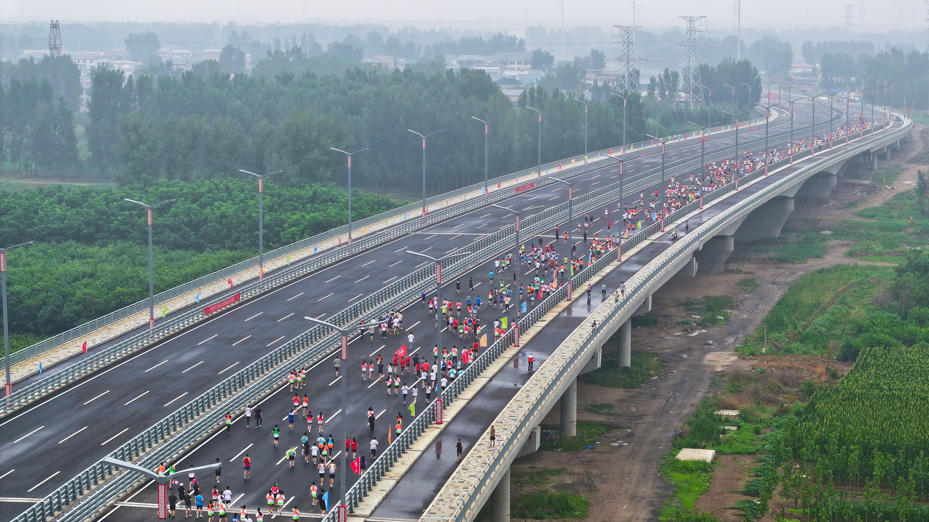 河北涿州：騰飛大街北延跨北拒馬河大橋建成通車_fororder_7月1日，河北省涿州市騰飛大街北延跨拒馬河大橋正式通車。圖為市民在大橋上健康跑（航拍照片）。熊華明攝