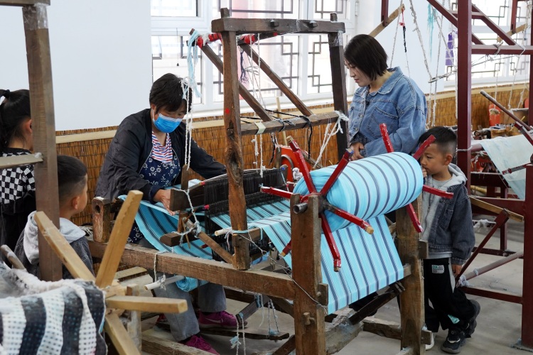 河北遷安融合創新點燃全域旅遊新引擎_fororder_遊客在遷安市繡娘非遺文化園感受傳統手工織布技藝，韓春東 攝