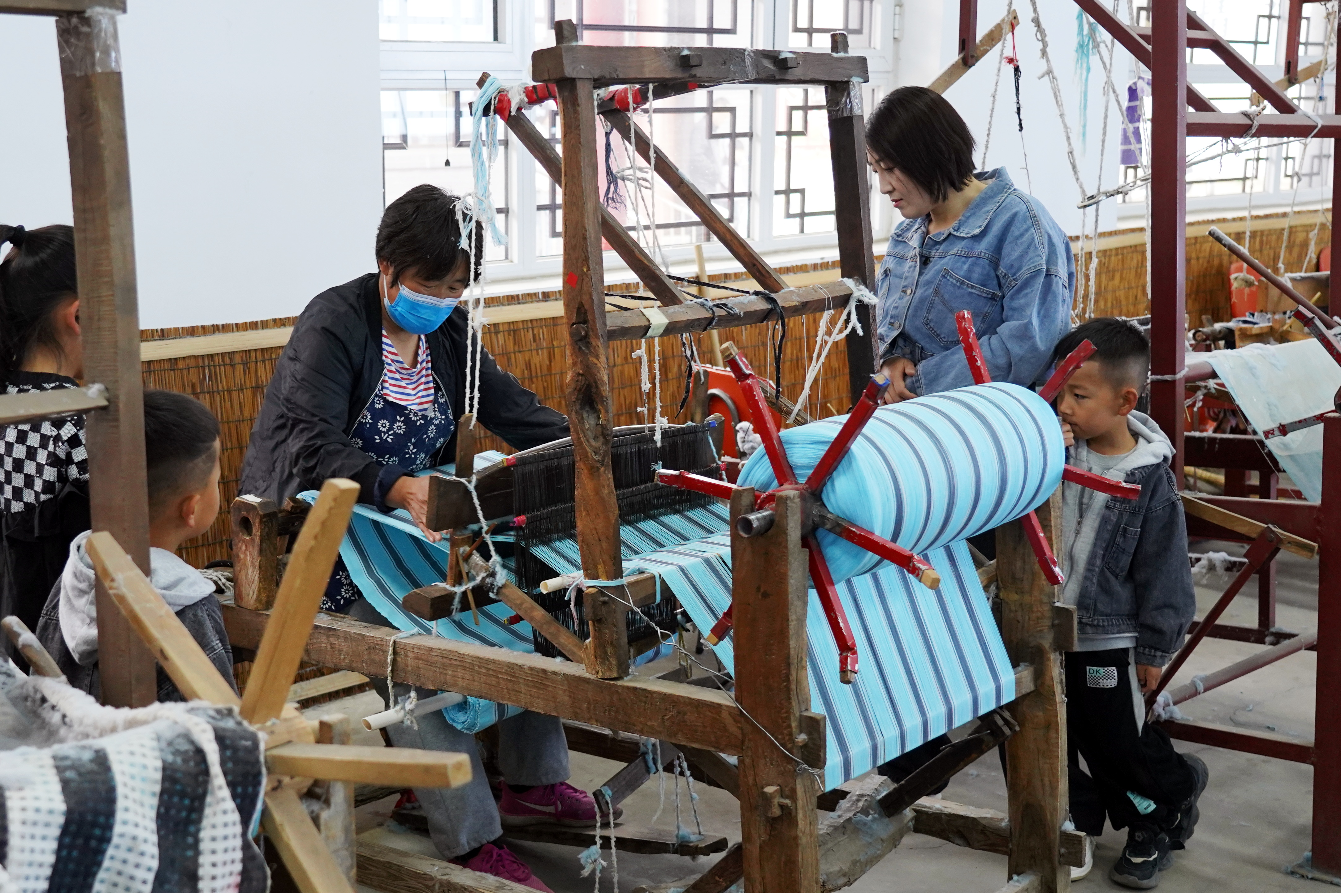 河北遷安融合創新點燃全域旅遊新引擎_fororder_遊客在遷安市繡娘非遺文化園感受傳統手工織布技藝，韓春東 攝