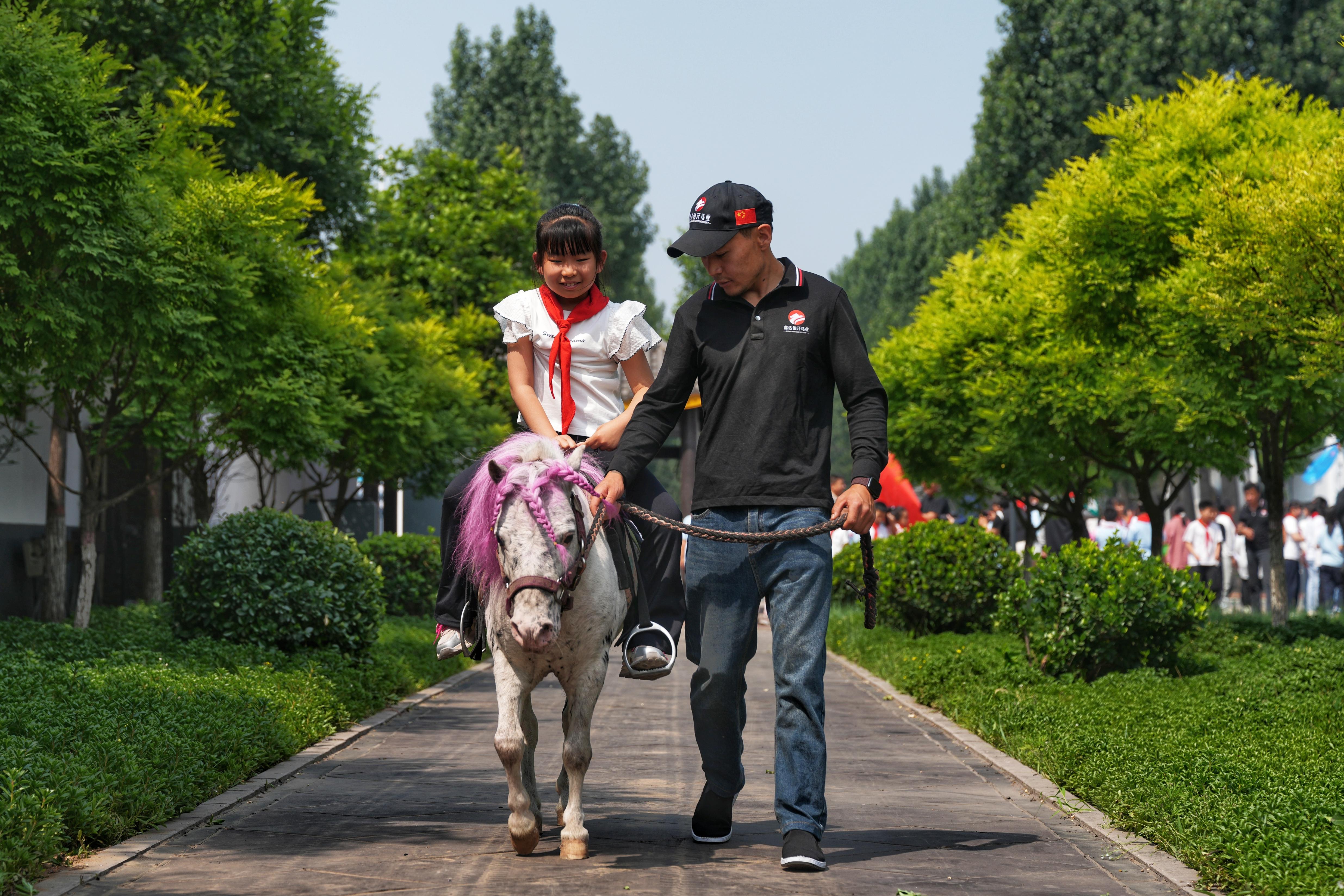 河北遷安：趣味研學遊 “馬”上迎“六一”_fororder_5月27日，同學們在教練的帶領下體驗騎馬。張澤慧攝（2）