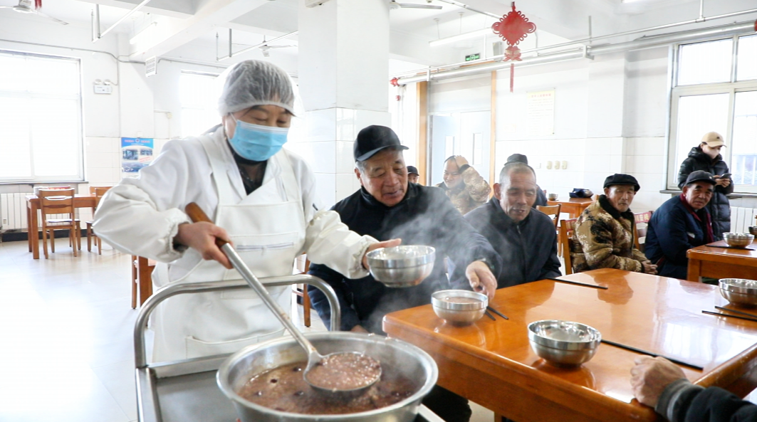 河北遷安：臘八粥香漫全城 志願溫情暖人心_fororder_在遷安市第三福利院，老人在一起品嘗臘八粥。王志斌 攝
