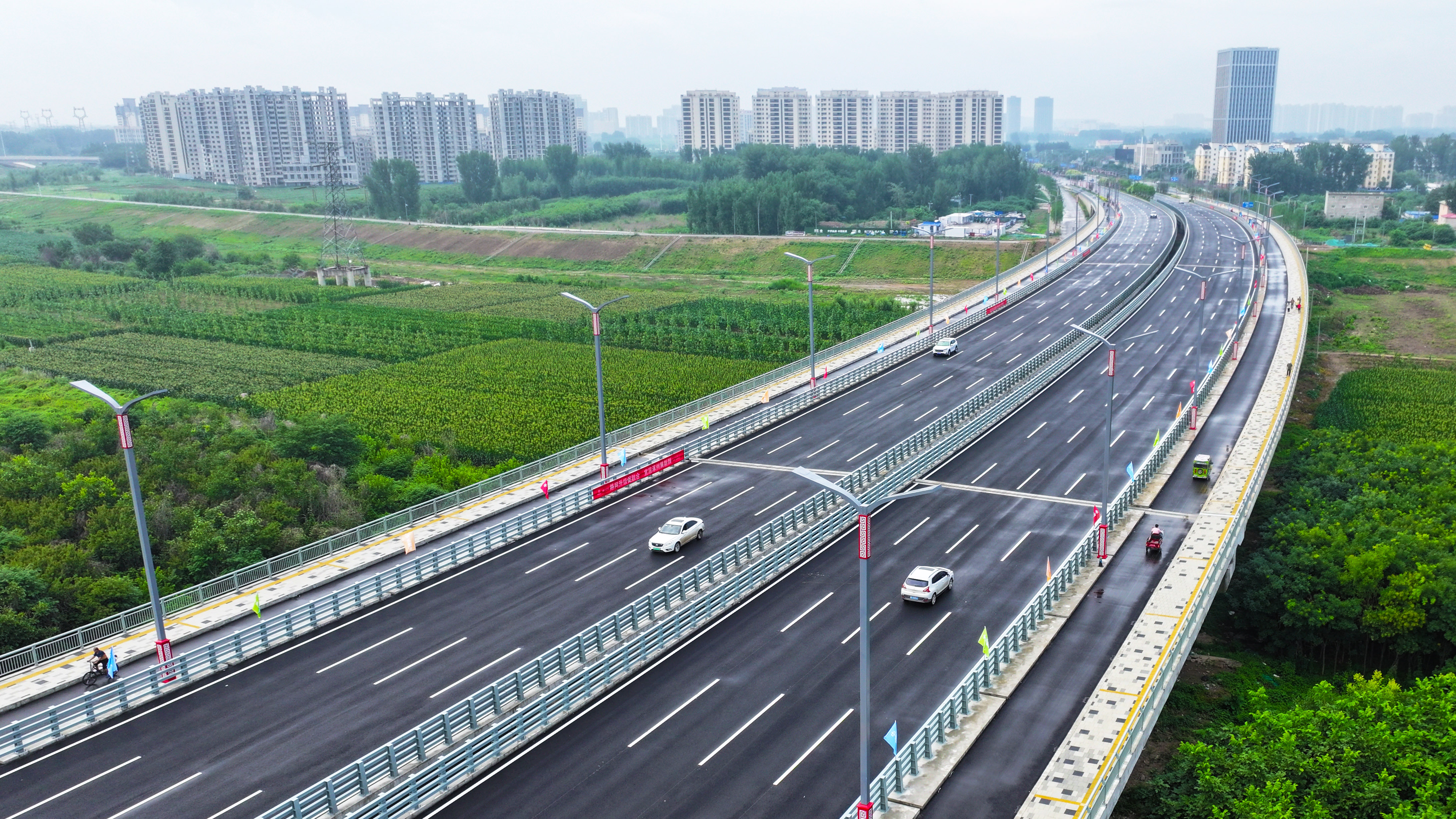 河北涿州：騰飛大街北延跨北拒馬河大橋建成通車_fororder_7月1日，河北省涿州市騰飛大街北延跨拒馬河大橋正式通車。圖為車輛在大橋上通行（航拍照片）。熊華明攝