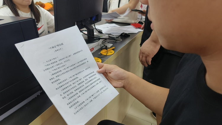 圖片默認標題_fororder_圖片為辦事群眾閱讀個體工商戶明白紙。鞠義攝
