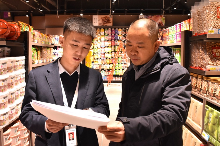 河北清苑：超前輔導為企業解難題_fororder_工作人員為超市經營者講解食品經營許可證的辦理流程。 趙琪攝.JPG