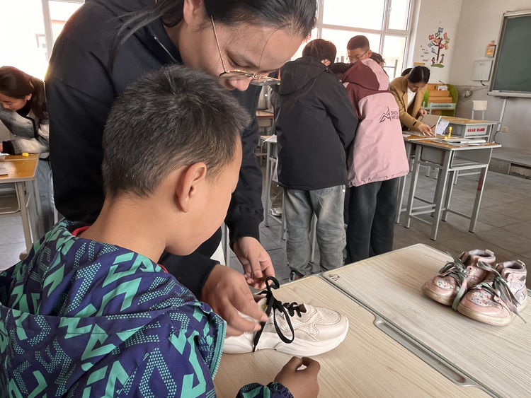 河北唐縣：優化課後服務 助力多彩童年_fororder_勞動技能賽上，老師教學生如何繫鞋帶