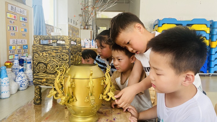 河北唐縣：探秘青銅文化 觸摸歷史之美_fororder_孩子們正圍在一起近距離觀察青銅器模型的結構和花紋