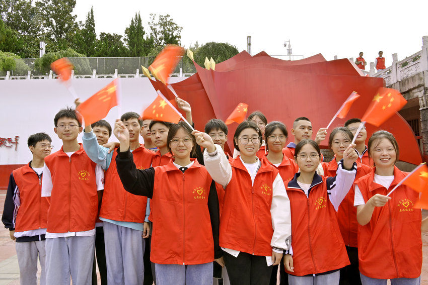 信陽市新縣：國慶假期 紅色旅遊受青睞_fororder_新縣紅細胞志願服務隊的志願者揮舞著國旗（焦漢平 攝）