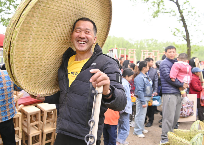 信陽市新縣：非遺大市集熱鬧開市_fororder_扛著購買的竹篩喜笑顏開（焦漢平 攝）