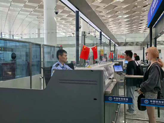 “鄭”值濃情端午節 鄭州邊檢守國門優服務護口岸穩序運轉_fororder_鄭州邊檢站民警為旅客辦理出入境通關手續（王晗攝）