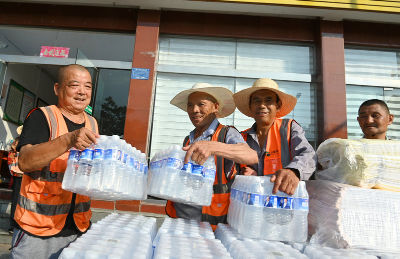 信陽市新縣：夏日送清涼 關懷暖人心_fororder_正在搬運礦泉水等物品（焦漢平 攝）