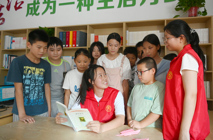 信陽市新縣：書香伴暑假 閱讀潤童心_fororder_大學生志願者領著孩子們感受閱讀樂趣（焦漢平 攝）