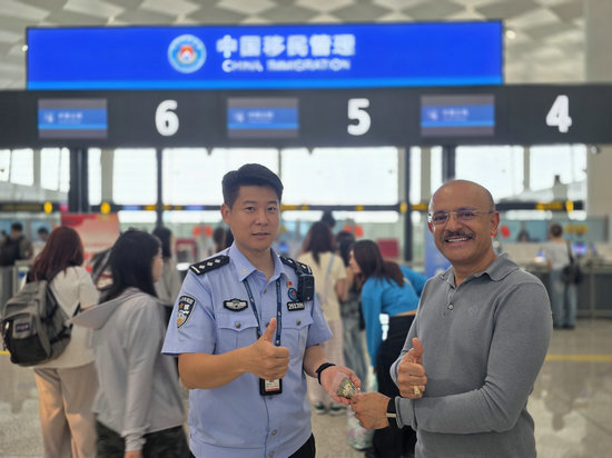 “鄭”值濃情端午節 鄭州邊檢守國門優服務護口岸穩序運轉_fororder_鄭州邊檢站民警向外籍旅客介紹端午節（王晗攝）