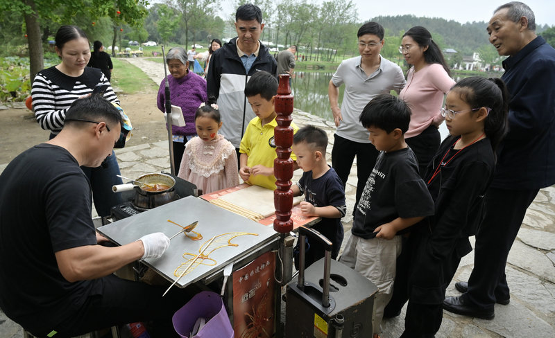 旅遊綜合收入近7億元 信陽市新縣國慶中秋假期文旅“成績單”亮眼_fororder_在丁李灣古村落,糖畫攤前吸引了遊客前來購買(焦漢平 攝)