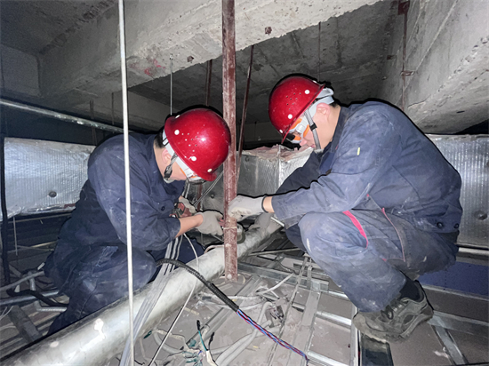 方大集團中興商業暖通科:為消費者築起“溫暖屏障”_fororder_在狹小的棚頂裏,中興商業暖通科員工在聚精會神地檢修設備-1 攝影:徐晨