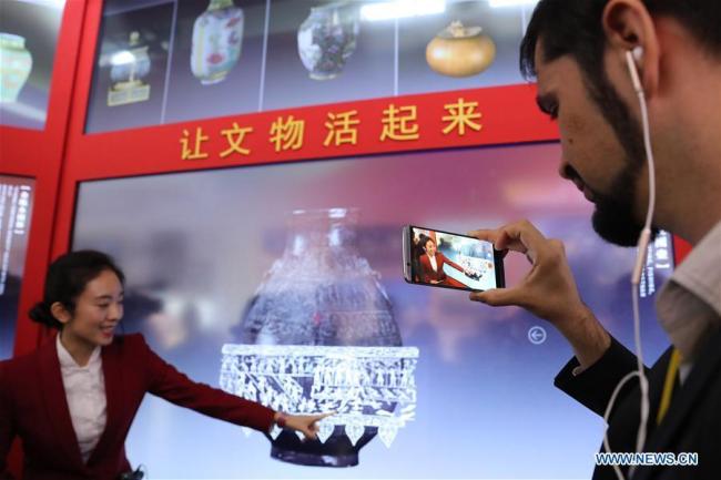 Un journaliste tourne une vidéo d'une présentation du Musée du Palais Numérique au Centre des expositions de Beijing, capitale de la Chine, le 16 octobre 2017.