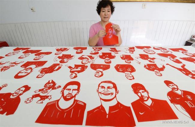  Feng Shiping, artiste spécialisée dans le papier découpé, réalise des oeuvres pour accueillir la Coupe du monde, à Handan, dans la province chinoise du Hebei (nord), le 12 juin 2018. (Photo : Hao Qunying)