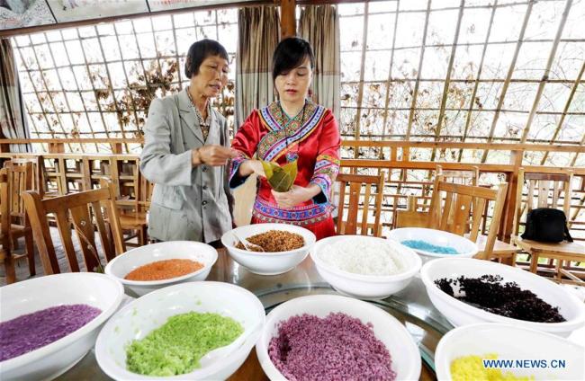 Des habitantes préparent des zongzi colorés, gâteaux de forme pyramidale composés de riz gluant emballé dans des feuilles de bambou ou de roseau, à l'approche de la Fête des bateaux-dragons, dans le district de Rong'an de la région autonome Zhuang du Guangxi (sud), le 12 juin 2018. (Photo : Tan Kaixing)