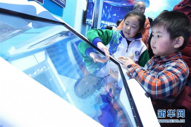 Deux jeunes visiteurs font l'expérience d'un projet interactif lors de l'exposition. Photo prise le 8 décembre.