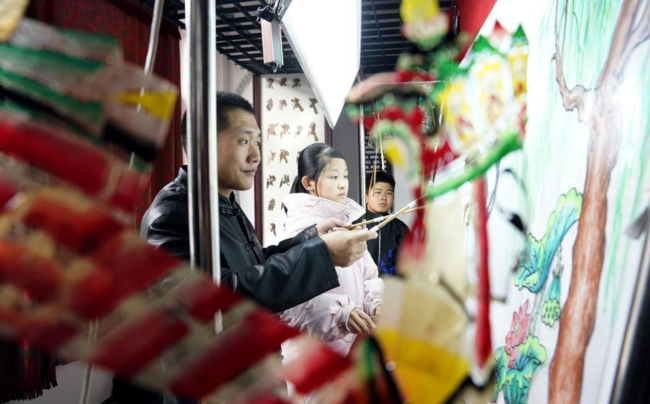 Guo Bao (l.) lehrt die Kinder in seinem Museum, Schattenpuppenspiele zu spielen.