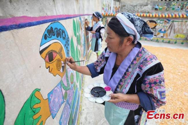 Ζωγράφοι της εθνότητας των Μιάο ζωγραφίζουν μια τοιχογραφία (壁畫 Bìhuà) στο χωριό Πινγκπό της κομητείας Λονγκλί της Αυτόνομης Νομαρχίας Τσιεννάν Μπουγί και Μιάο, στην επαρχία Γκουιτζόου της νοτιοδυτικής Κίνας, στις 15 Σεπτεμβρίου 2021