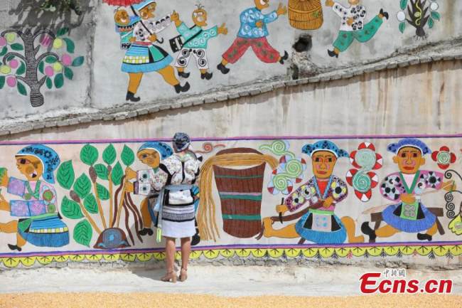 Ζωγράφος της εθνότητας των Μιάο επιδιορθώνει τοιχογραφίες (壁畫 Bìhuà) που έχουν γίνει σύμφωνα με το στυλ των Μιάο στο χωριό Πινγκπό της κομητείας Λονγκλί της Αυτόνομης Νομαρχίας Τσιεννάν Μπουγί και Μιάο, στην επαρχία Γκουιτζόου της νοτιοδυτικής Κίνας, στις 15 Σεπτεμβρίου 2021