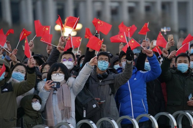 La gente agita las banderas nacionales chinas tras una gran ceremonia de izado de la bandera nacional en la Plaza de Tian´anmen en Beijing, capital de China, el 1 de enero de 2021.