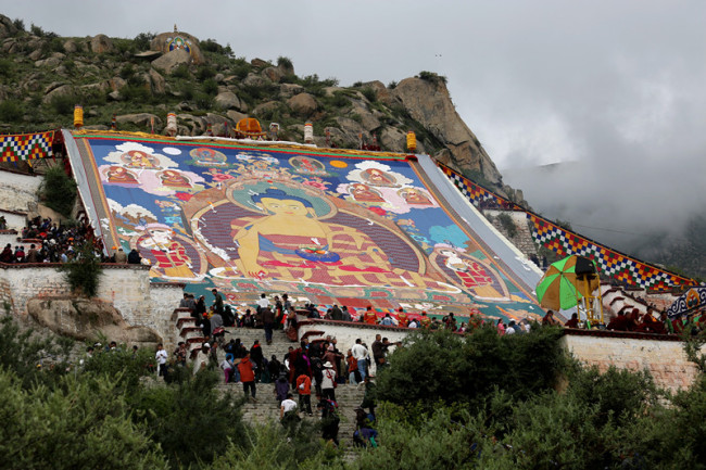 Des gens célèbrent le déroulement d'un thangka -une peinture religieuse géante en soie- à l'occasion du début du festival du yaourt, au monastère Drepung de Lhassa, capitale de la région autonome du Tibet (sud-ouest de la Chine), le 11 août 2018. (Palden Nyima / China Daily)