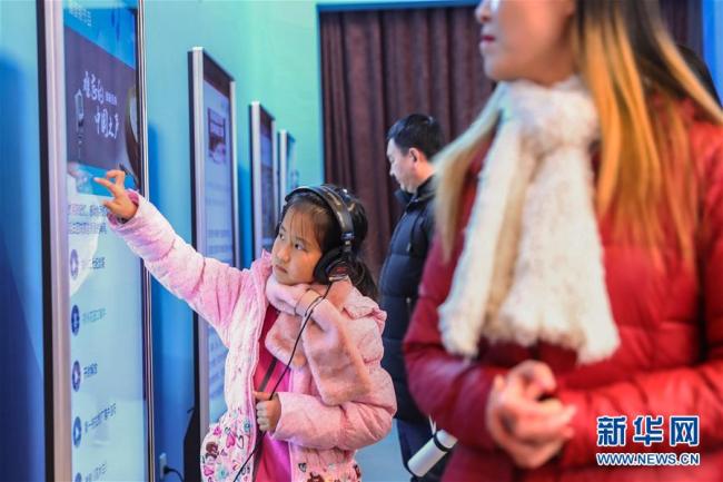 Une jeune visitueuse essaie un écran interactif lors de l'exposition. Photo prise le 8 décembre.