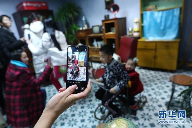 Des visiteurs utilisent leur téléphone portable pour photographier deux enfants dans le « Musée du temps ». Photo prise le 8 décembre.