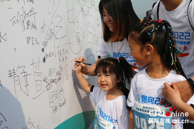 Les enfants qui participent à la course familiale écrivent leurs noms sur le mur de signature