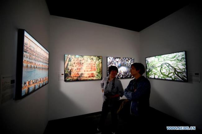  Des visiteurs admirent des photos exposées lors du 17e Festival international de l'art photographique de la Chine à Zhengzhou, capitale de la province centrale du Henan, le 19 mai 2018. (Photo : Zhu Xiang)