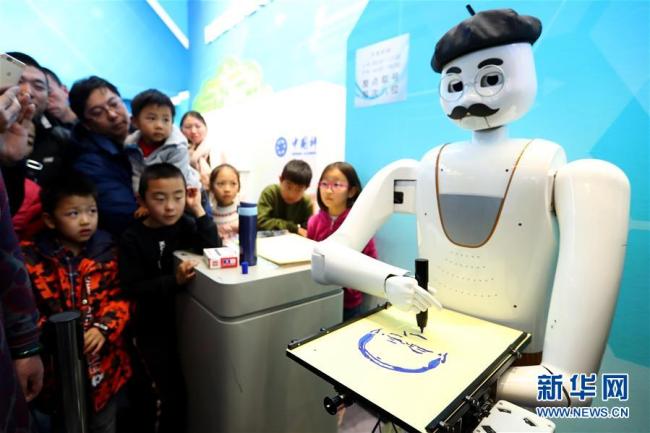 Des visiteurs regardent un robot intelligent portraitiste en train de « créer ». Photo prise le 8 décembre.