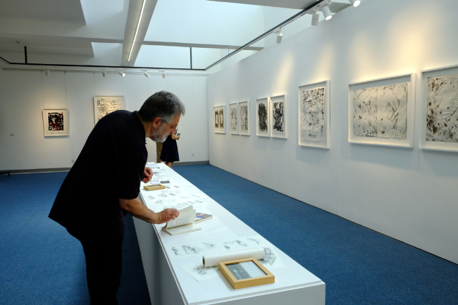 Un visiteur admire les tableaux de Paul Andreu