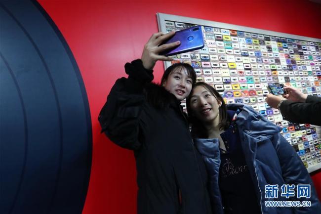 Deux visiteuses prennent un selfie devant un mur de cassettes audio. Photo prise le 8 décembre.