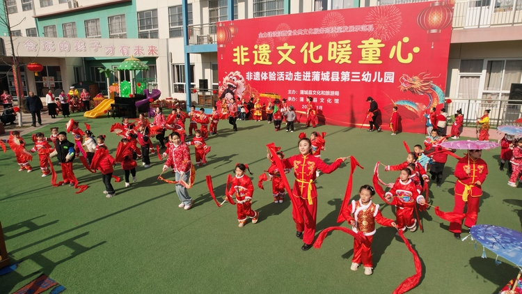 年味非遺進校園_fororder_2024年1月11日，陜西省渭南市蒲城縣開展“社火·廟會”非遺進校園活動中孩子們與老師家長一同扭起大秧歌