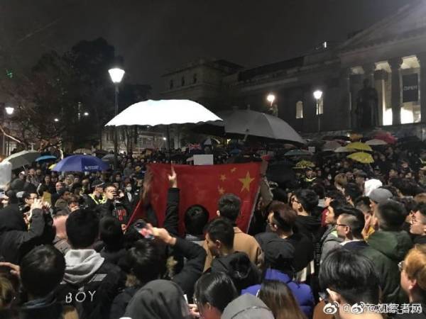 中國留學生高唱國歌壓制“港獨” 冒雨為國旗撐傘